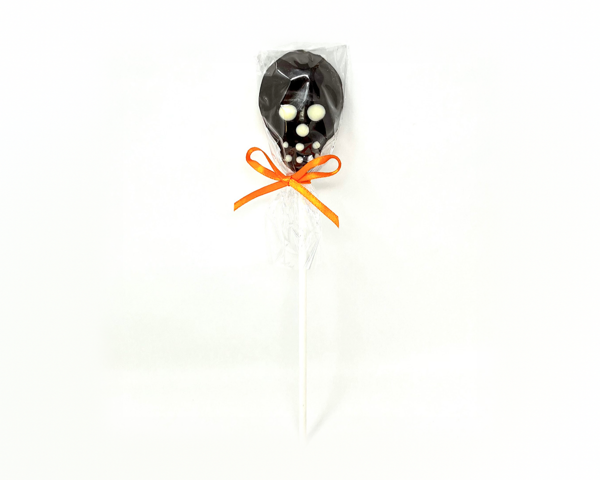 Chocolate skull lollipop, hand decorated, wrapped in cellophane with an orange bow